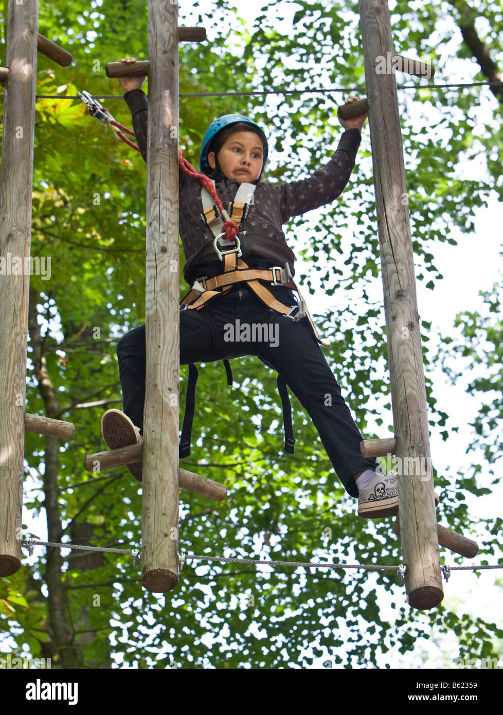 Young girl, ca. 11, climbing with a fearful expression between two