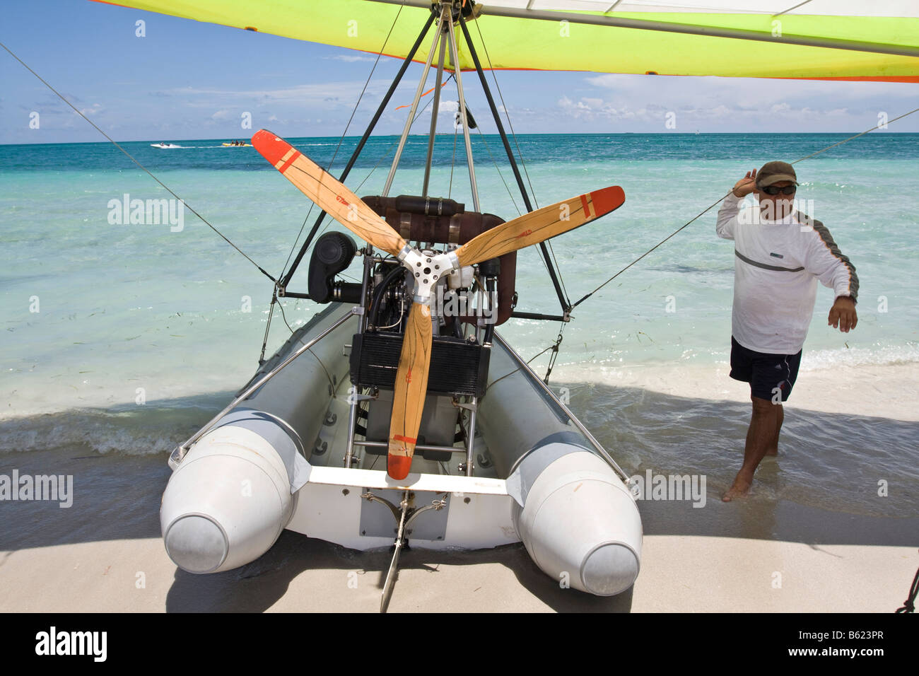 Pilot of a motorised hang glider waiting for passengers on a beach, UL