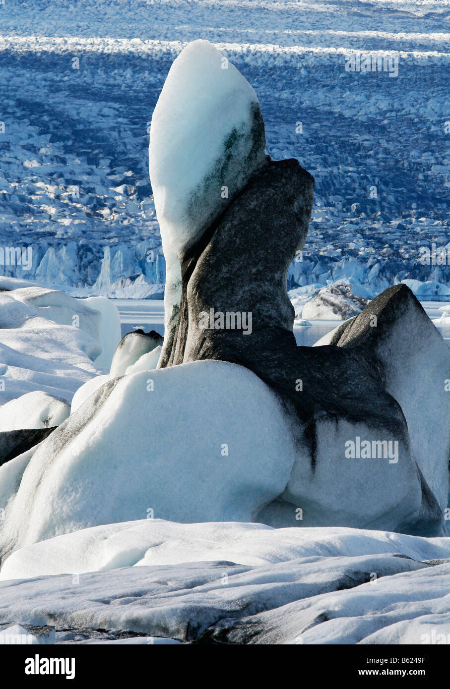 Floating iceberg, ice sculpture, coloured with black lava ash, in the Joekulsarlon glacier lagoon of the Vatnajoekull Glacier,  Stock Photo