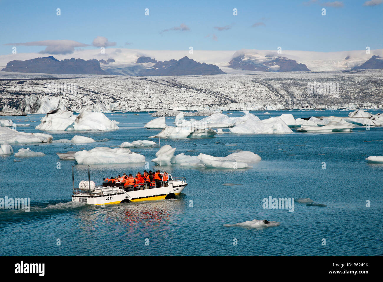 In the Joekulsarlon glacier lagoon of the Vatnajoekull Glacier, people travelling in an boat between the floating icebergs, whi Stock Photo