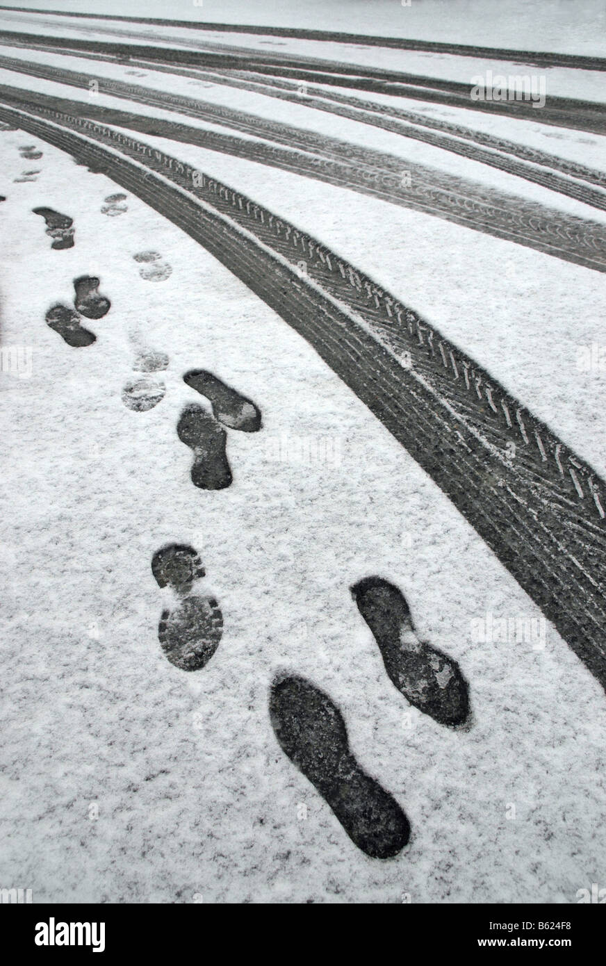 Car tyre marks and footprints in shallow snow. Stock Photo