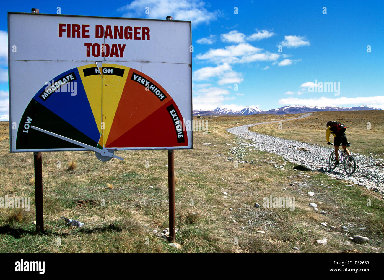 Mountainbiker riding past a Fire Danger sign, Lindis Pass, South Island, New Zealand Stock Photo