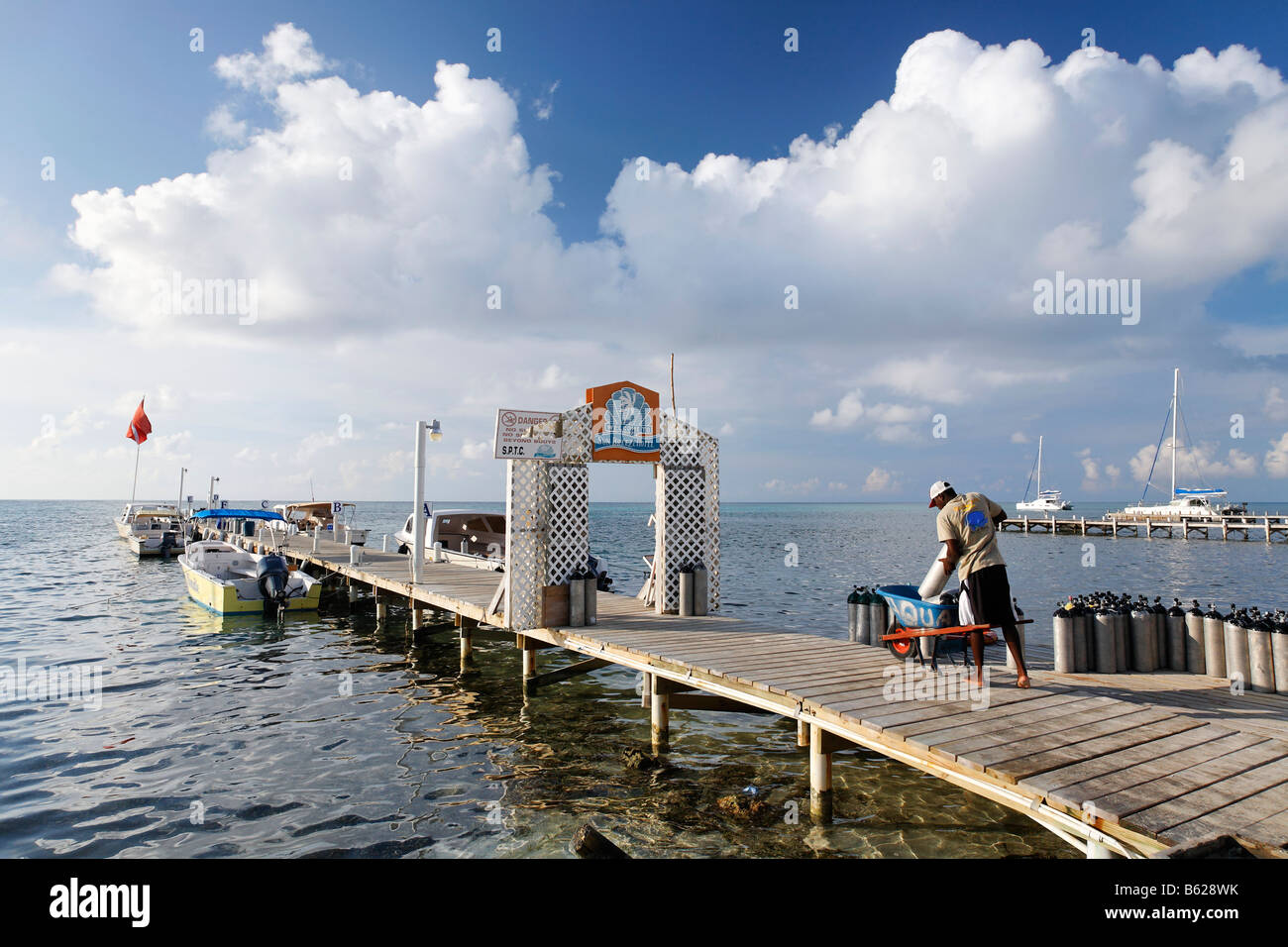 Scuba diving equipment being loaded into a trolley by a man on a pier, San Pedro, Ambergris Cay Island, Belize, Central America Stock Photo