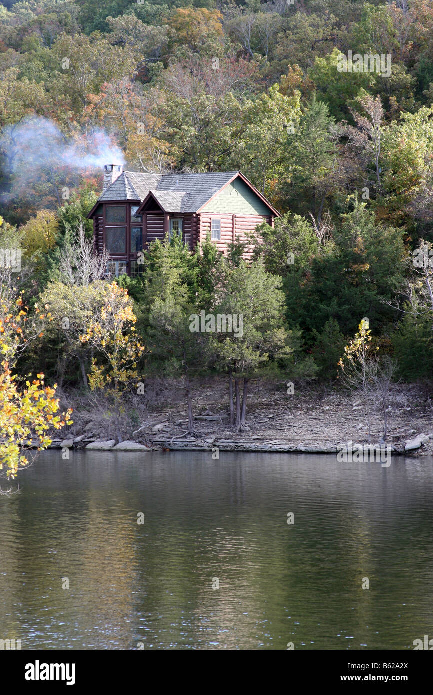 A Log Cabin On The Cliff Above A Lake During The Fall Season In