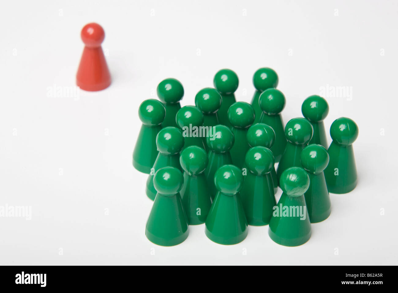 A group of green game pegs and a single red one, symbol for social isolation Stock Photo