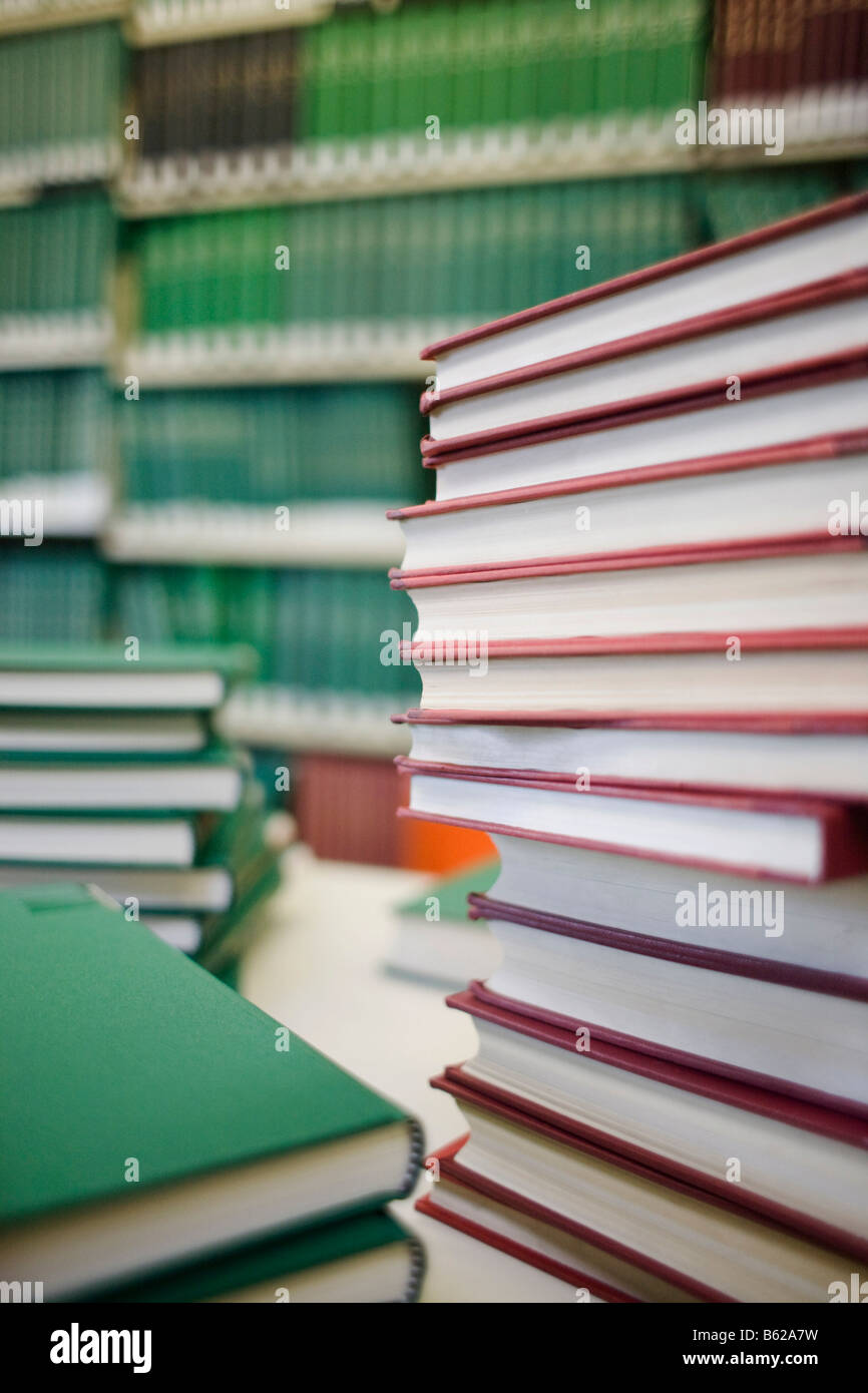 Piles of books in front of a shelf in a library Stock Photo