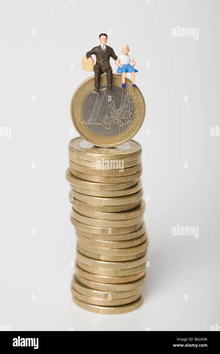 Father and daughter figures sitting on a pile of euro coins, symbolic for family budget Stock Photo