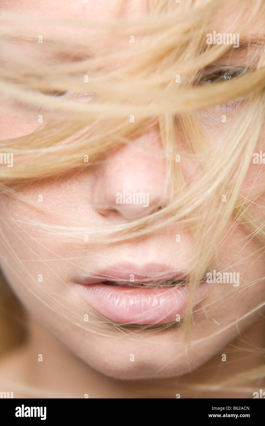 Young blond woman, hair partly covering her face, facial close-up Stock Photo