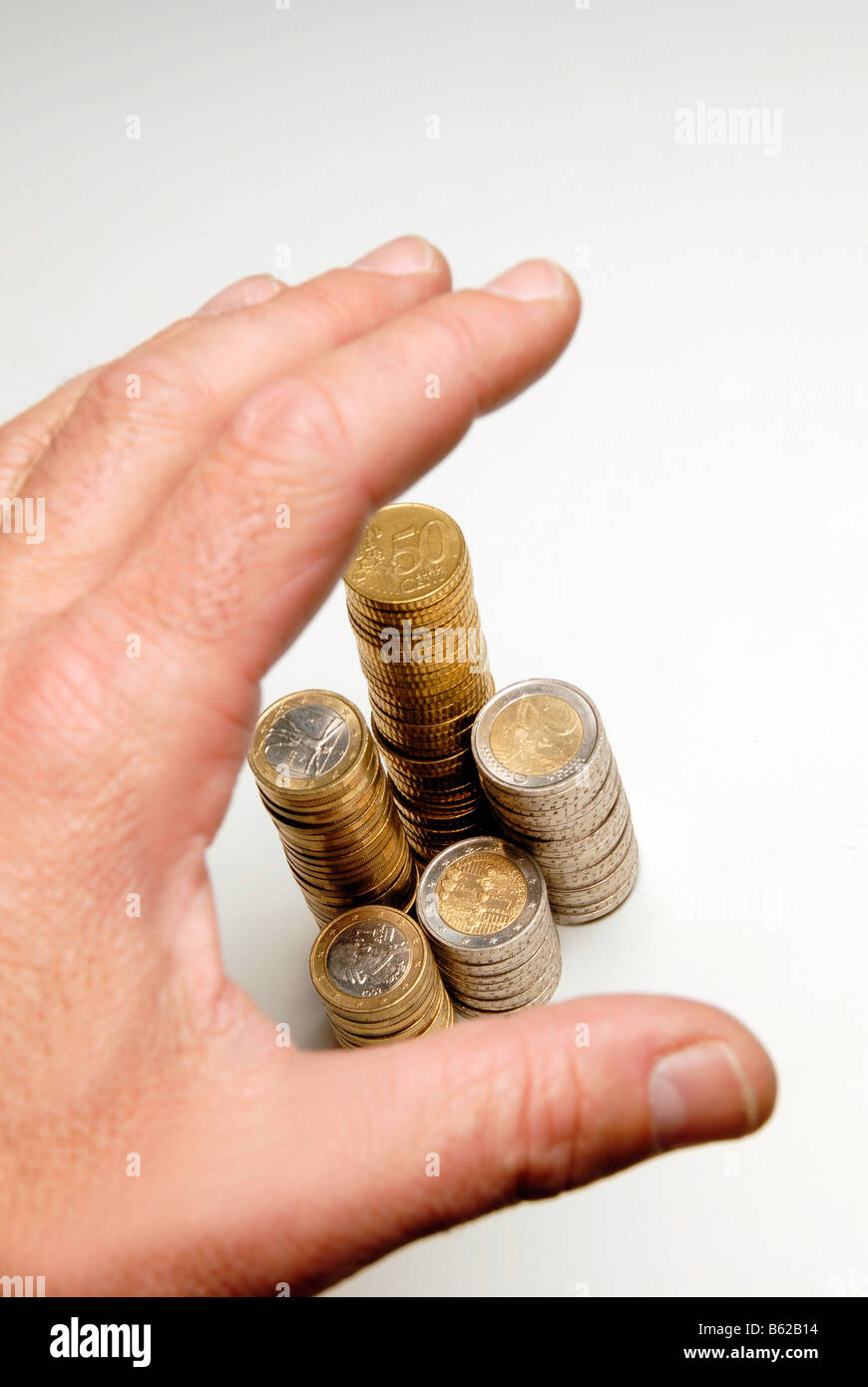 Hand above a pile of coins Stock Photo