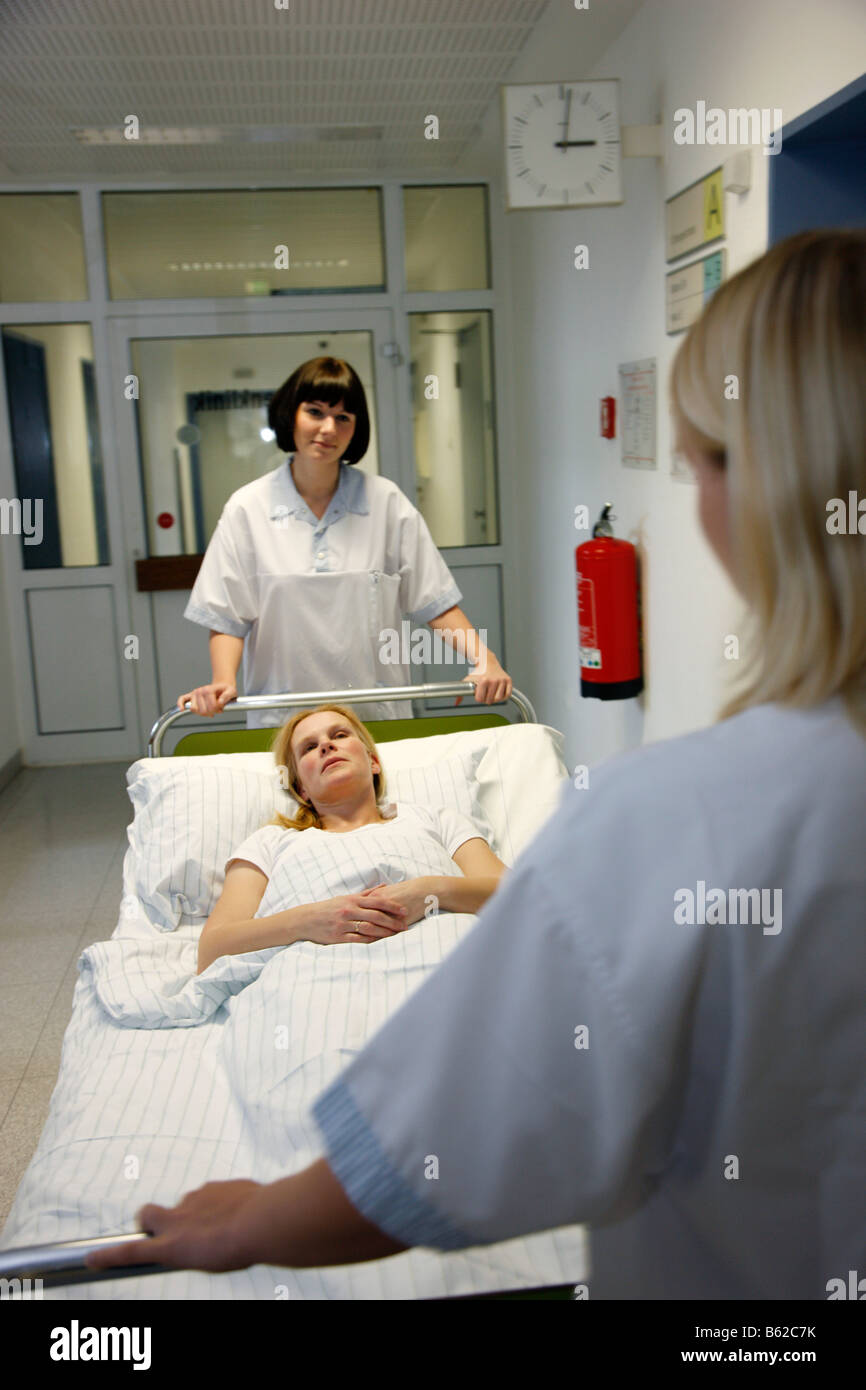 Patient is moved by nurses in her bed over a hospital floor Stock Photo