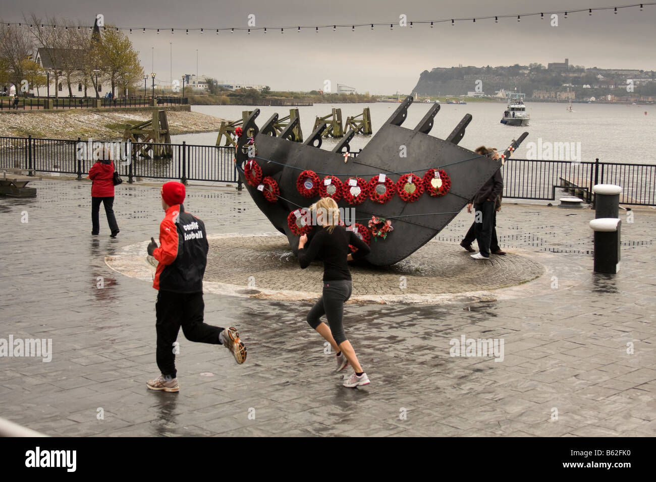 Joggers running past the war memorial in Cardiff Bay, Wales, United Kingdom Stock Photo