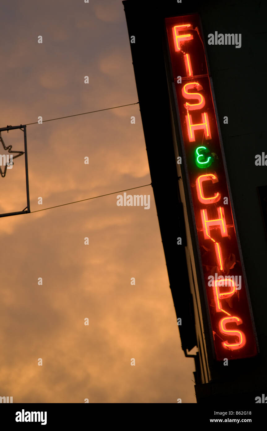 Strange light on Mammatus Mammatocumulus clouds in the sky at sundown with an illuminated neon sign for a fish and chip shop UK Stock Photo
