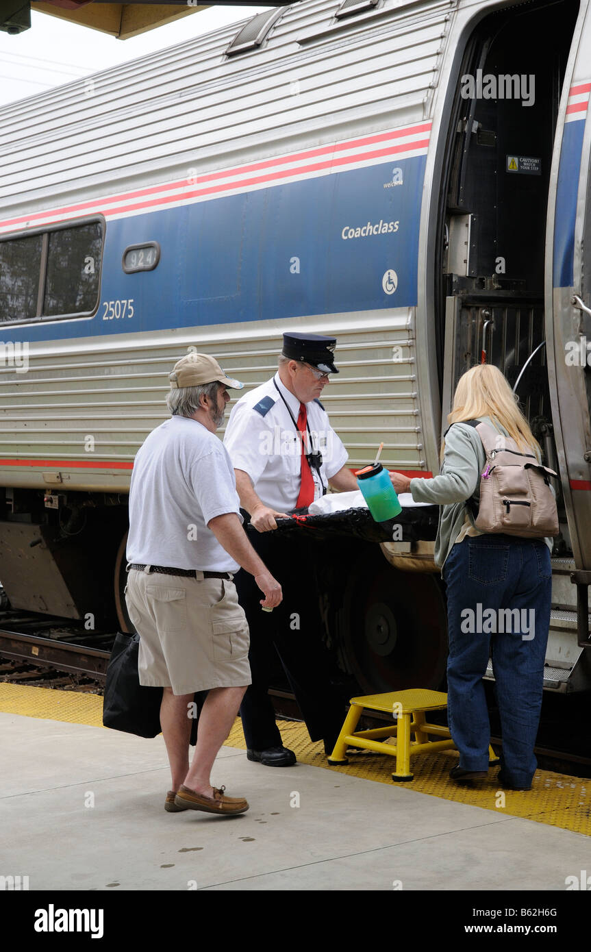 Amtrak railroad conductor assisting passengers onto train DeLand Train