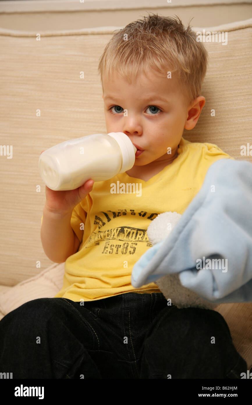 2 year old boy getting ready for bed with his bottle of milk and comfort blanket Stock Photo