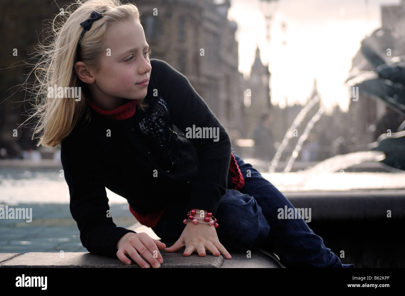 Royalty free photograph of young girl posing for photograph as a tourist in Trafalgar Square London UK Stock Photo