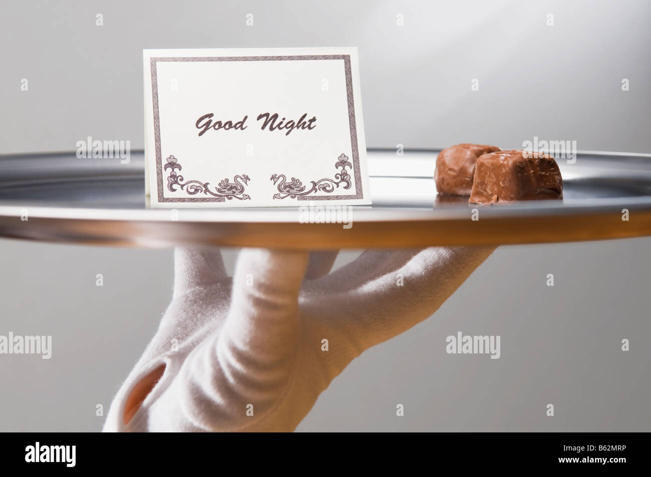 Close-up of a person's hand carrying sweet food and good night note in a plate Stock Photo