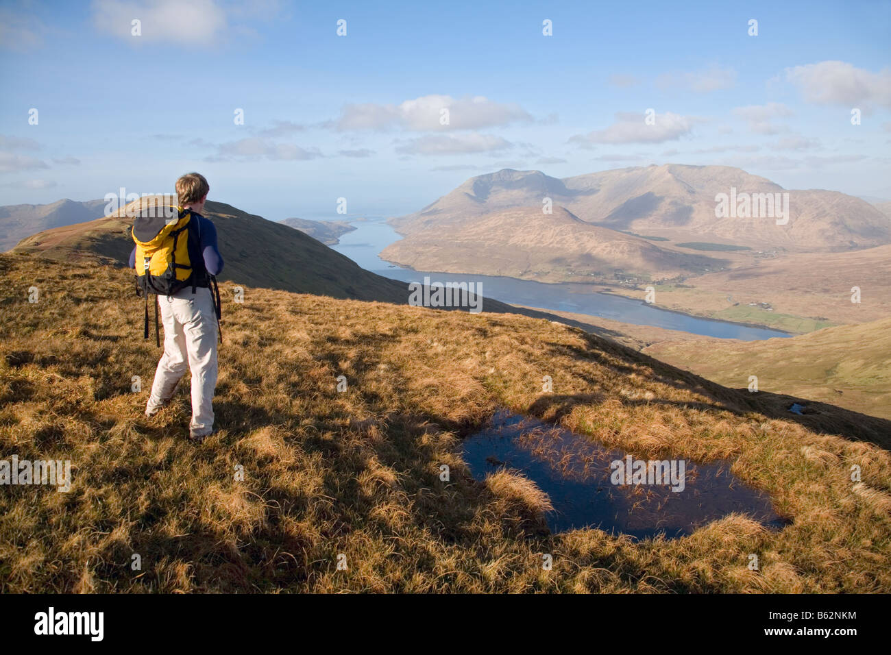 Hiker looking over Killary Harbour from Leenaun Hill, Maumturk Mountains, Connemara, County Galway, Ireland. Stock Photo