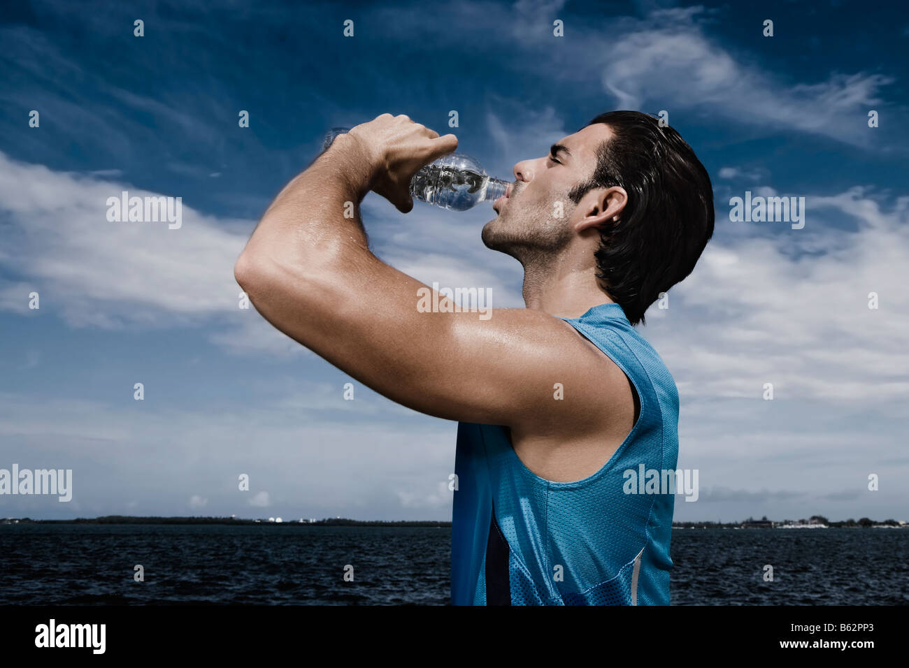 Side profile of a young man drinking water from a water bottle Stock