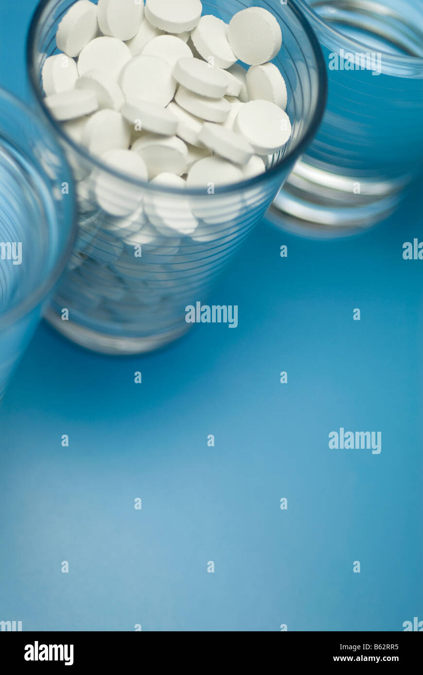 Close-up of a glass full of pills with two glasses of water Stock Photo