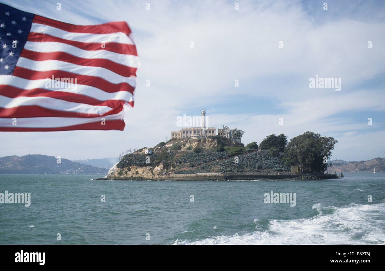 Alcatraz Island and prison, San Francisco Bay, seen from boat departing the island, with Stars and Stripes Stock Photo