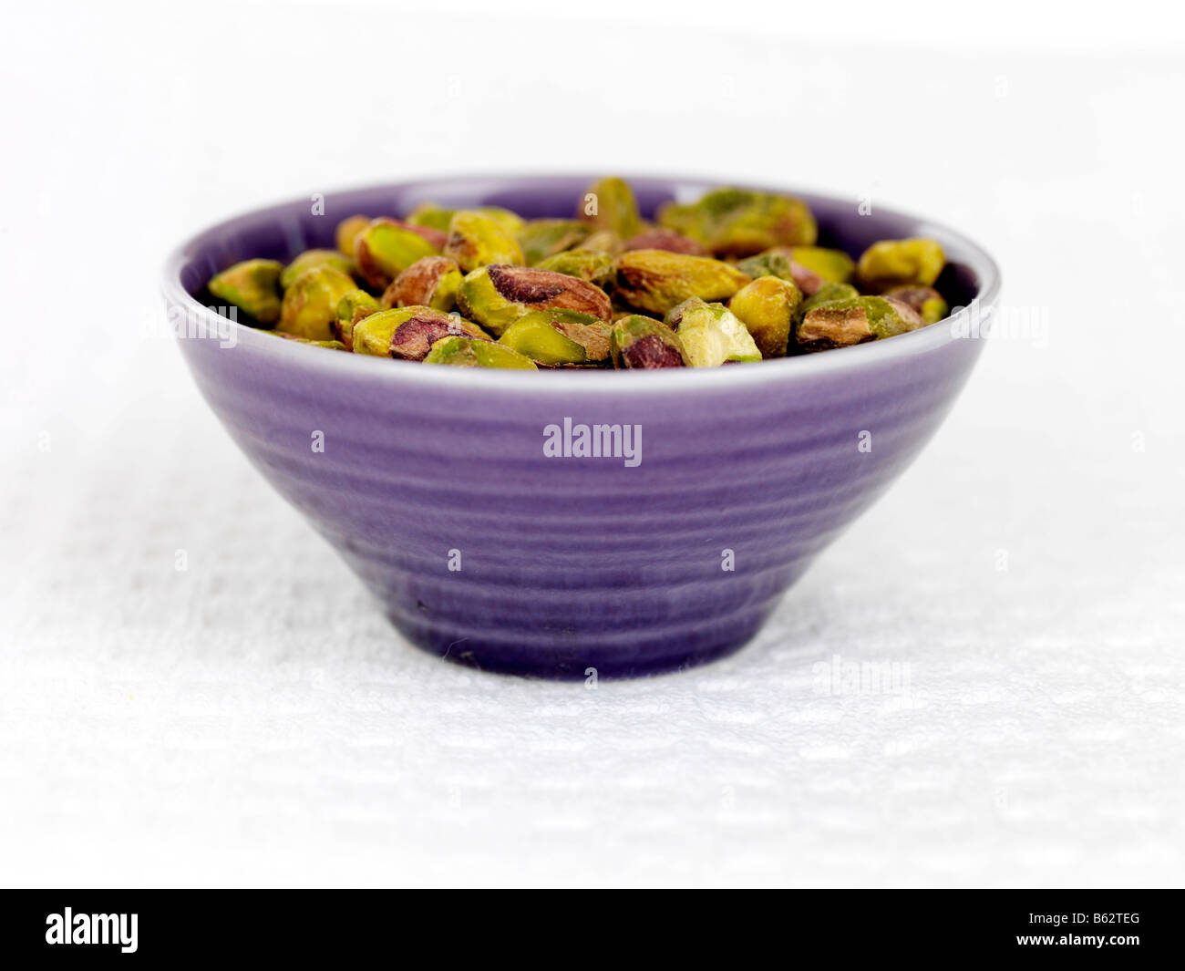 Fresh Shelled Green Pistachios Nuts In A Bowl Isolated Against A White