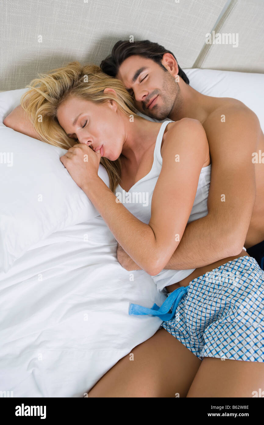 High angle view of a young man and a mid adult woman lying on the bed Stock Photo