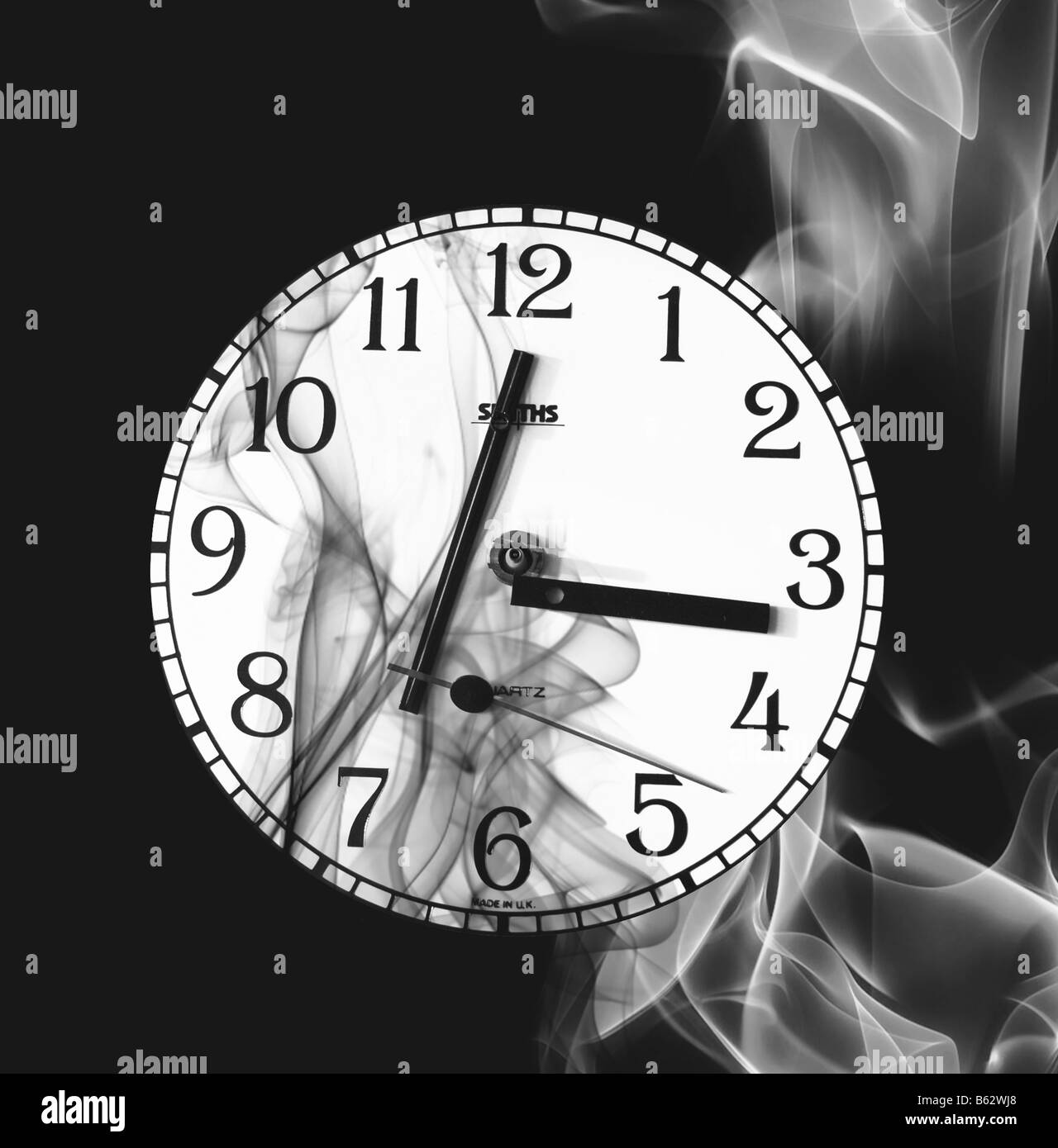 A clock face with disconnected time hands and with plumes of smoke surrounding it. Stock Photo