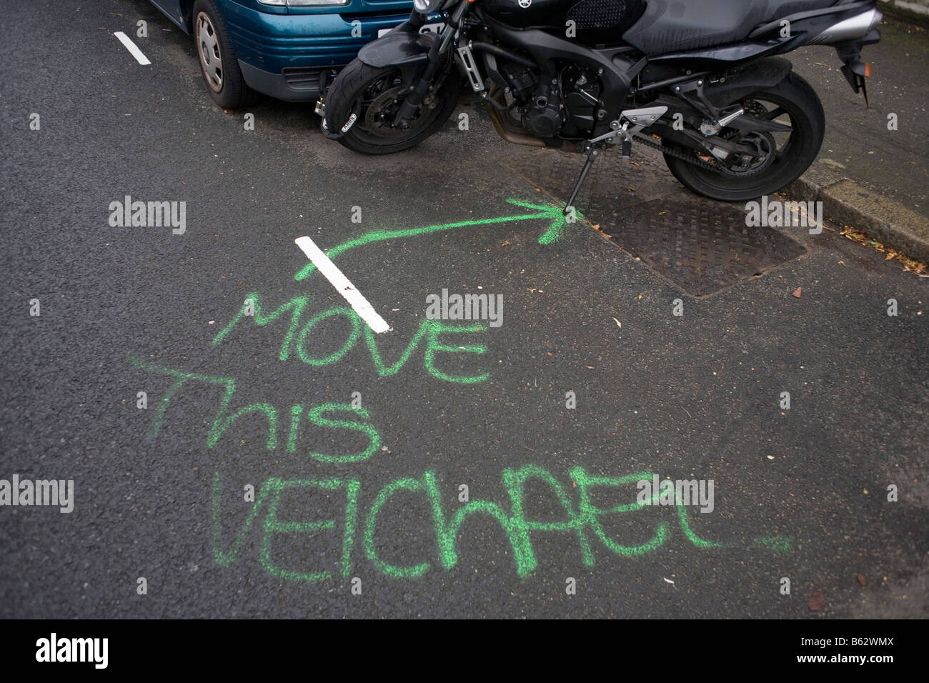 A request to move this vehicle has been mis-spelled by sprayed aerosol on the road's surface in a residential London street Stock Photo