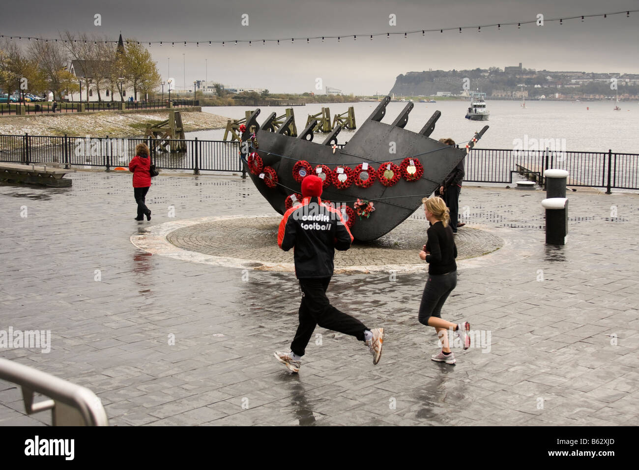 Joggers running past the war memorial in Cardiff Bay, Wales, United Kingdom Stock Photo