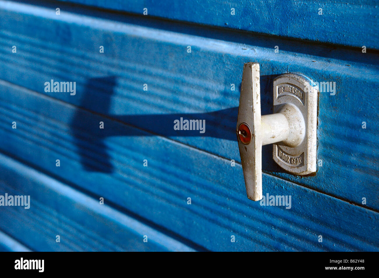 A locked garage door handle and its shadow. Stock Photo