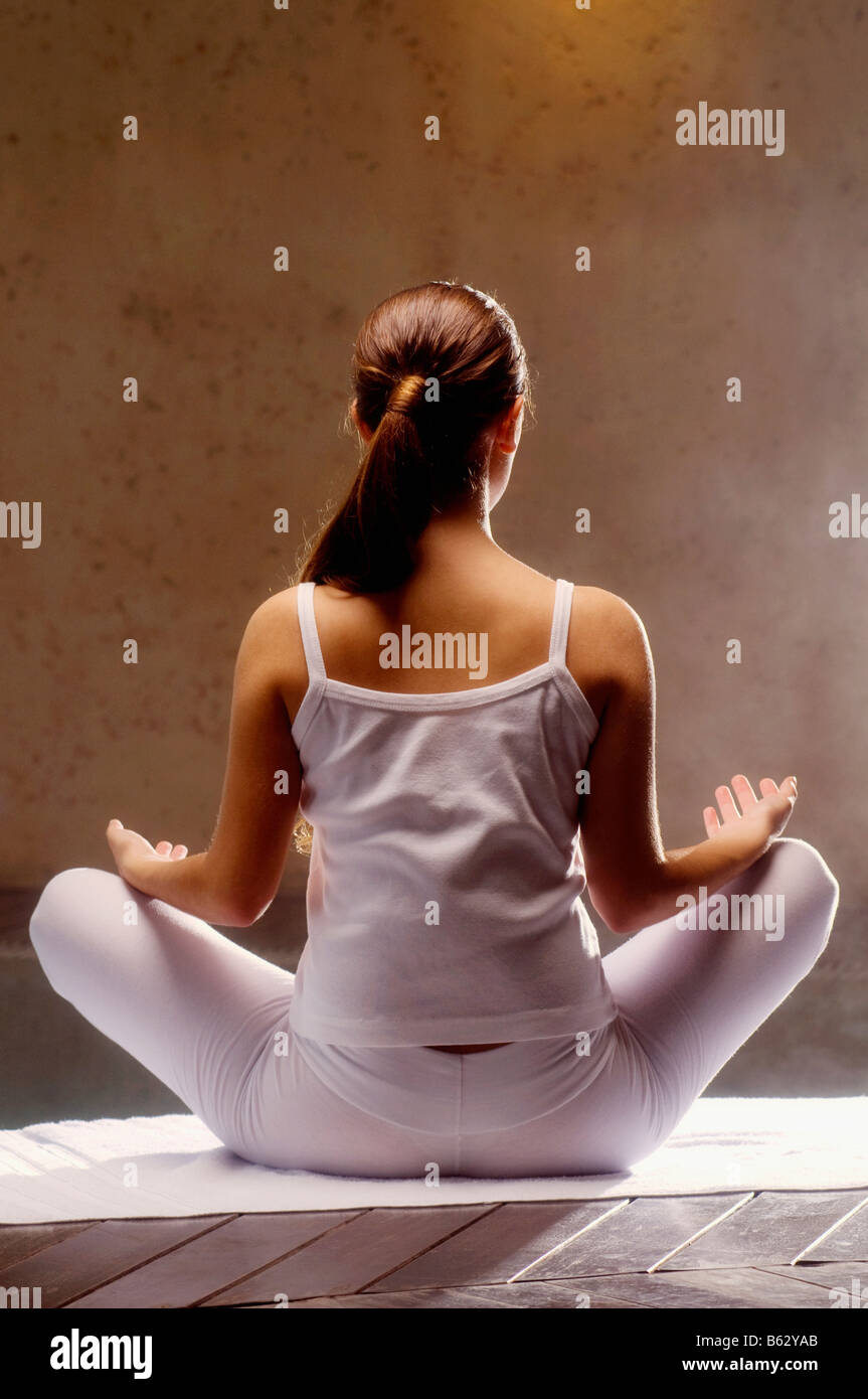 Rear view of a young woman meditating at the poolside Stock Photo