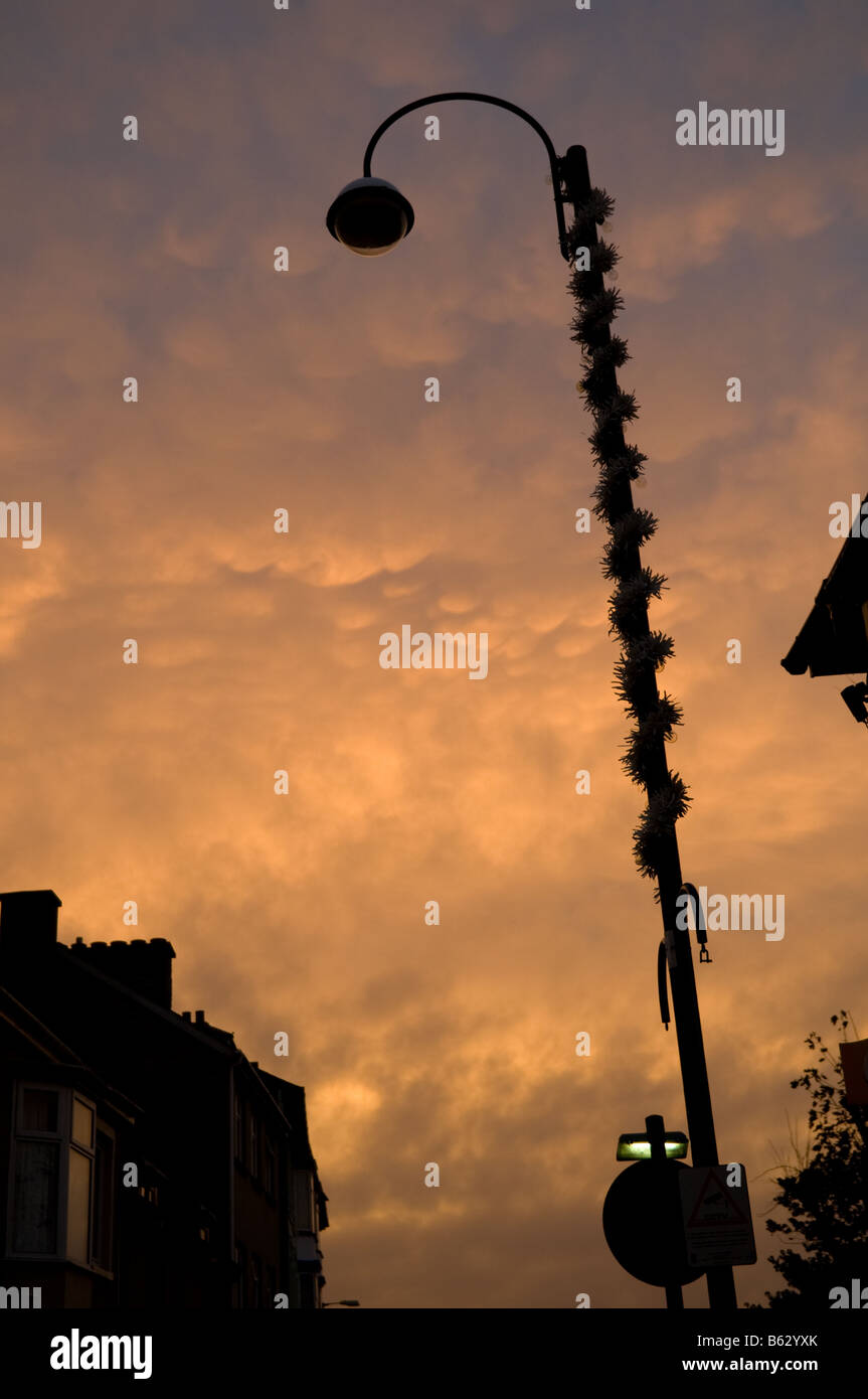 glowing light on underlit Mammatus clouds at sundown, moody oppressive eerie feeling, lamppost in silhouette, UK Stock Photo