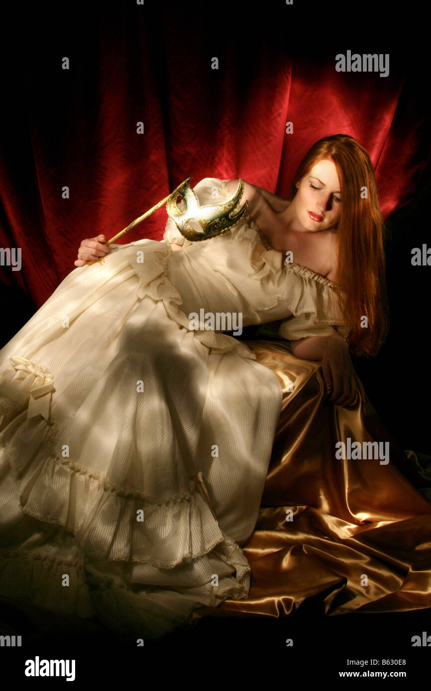 Light Painted Portrait of a Young Woman in a Ball Gown Holding a Venetian Mask Stock Photo