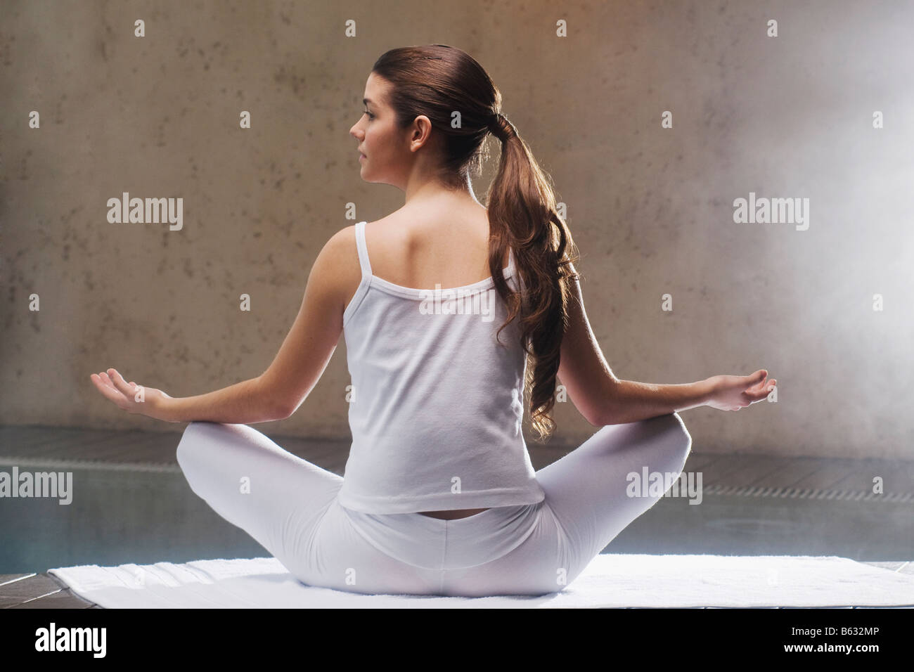 Rear view of a young woman meditating at the poolside Stock Photo - Alamy