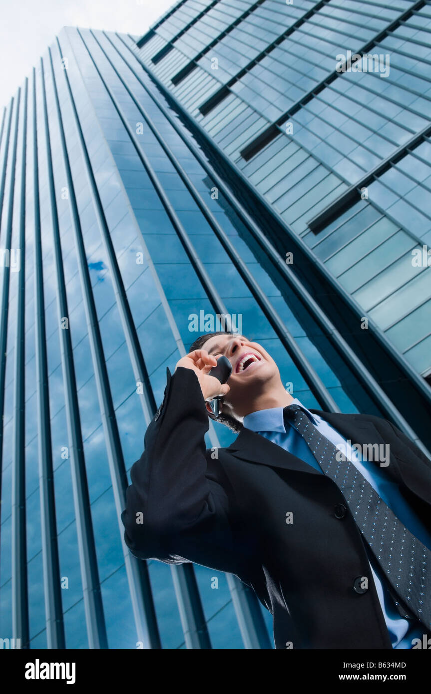 Low angle view of a businessman talking on a mobile phone and laughing Stock Photo