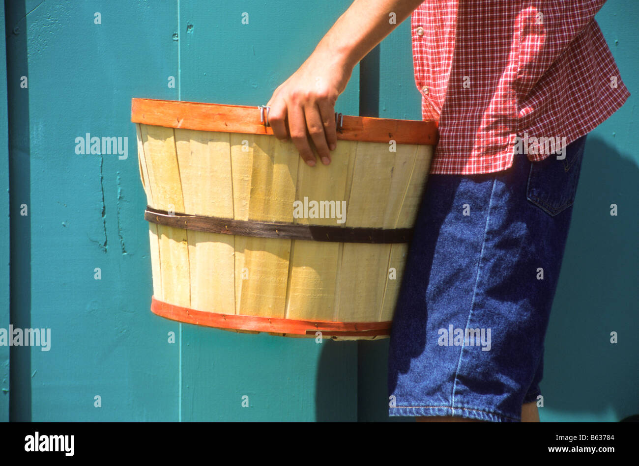 Hispanic boy carries bushel basket full of yellow bell peppers Stock Photo