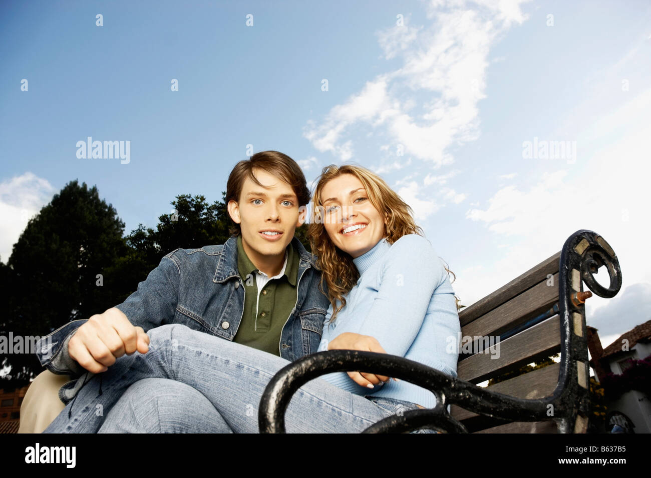 Portrait of a young couple sitting on a bench Stock Photo - Alamy