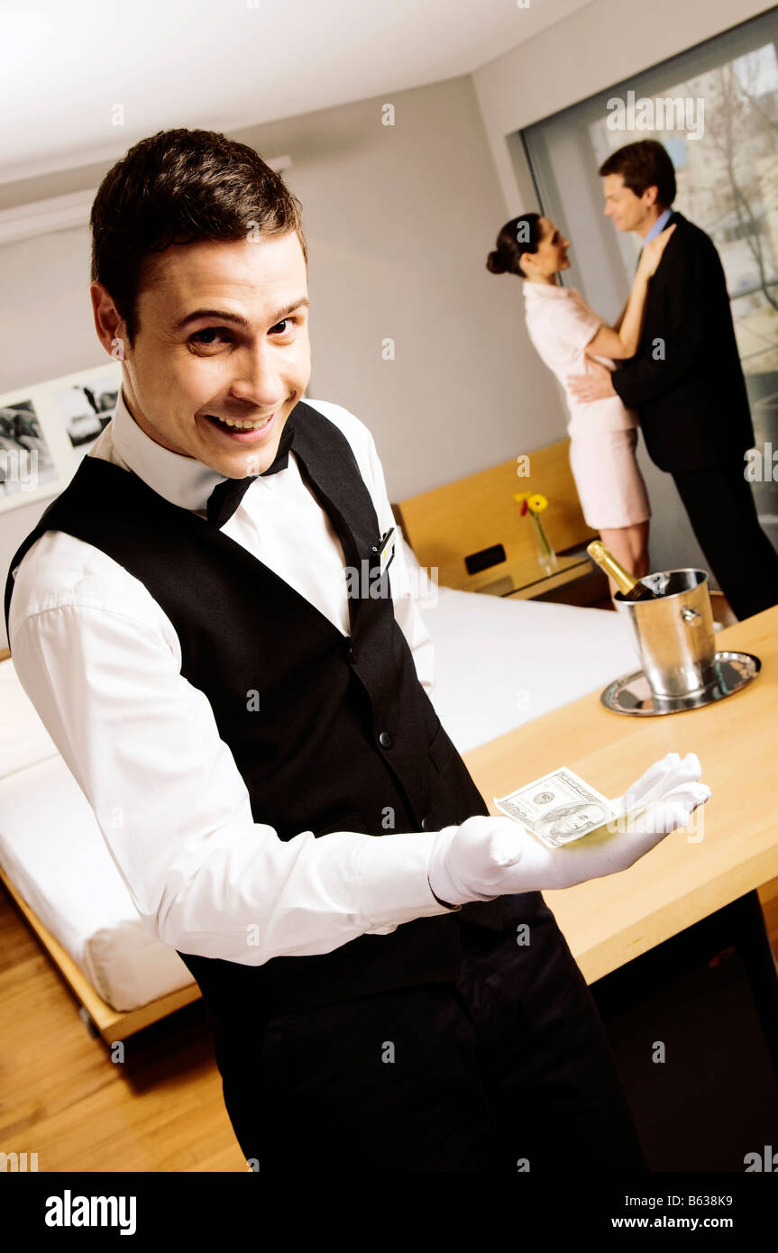 Portrait of a waiter holding us paper currency and smiling Stock Photo