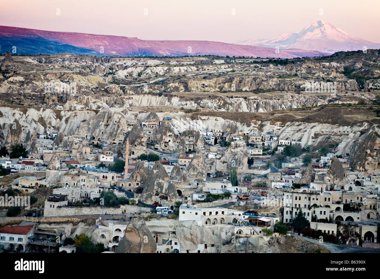 Goreme and Erciyes at Dusk. The white houses of Goreme fill the valley while snow covered Mount Erciyes shines Stock Photo