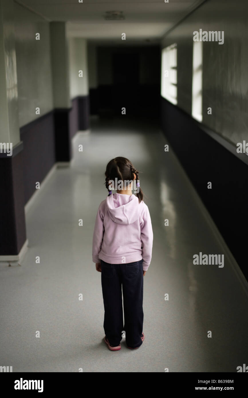 Five year old girl stands alone in school corricor Stock Photo