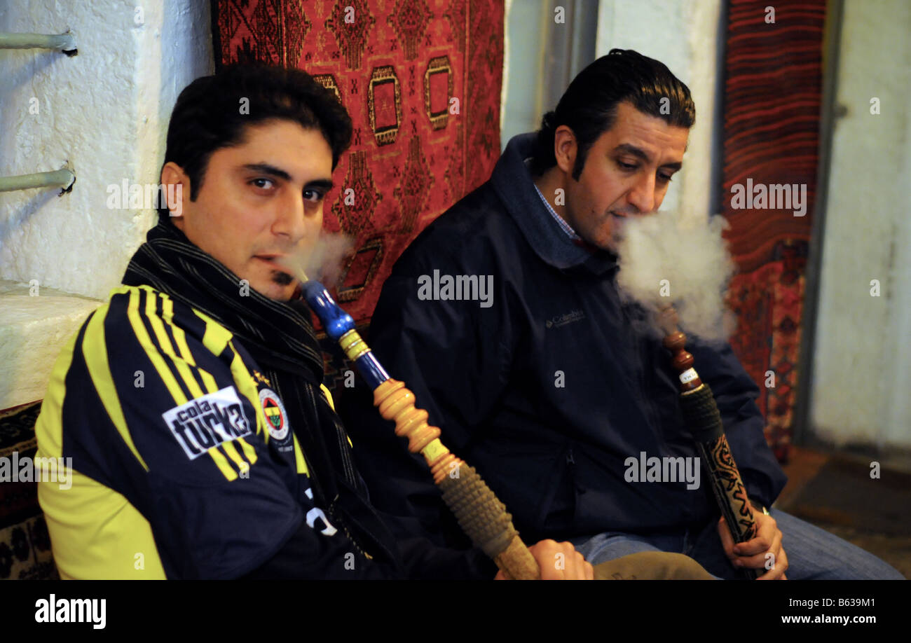 Two men smoke Nargila (water pipes) together near the Grand Bazaar in Istanbul, Turkey. Stock Photo