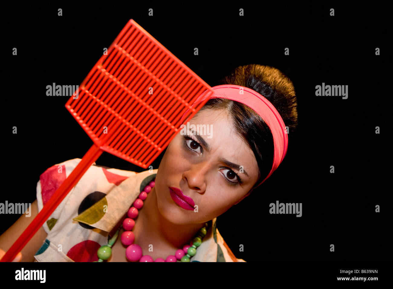 Portrait of a young woman holding a fly swatter Stock Photo