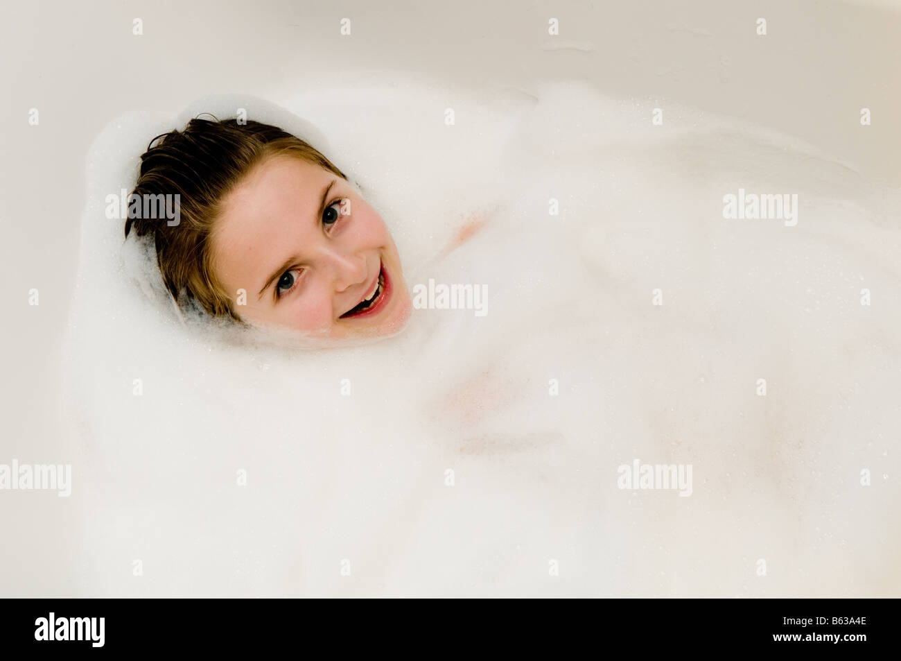 Ten year old girl in the bath looking happy smiling cheeky and cute