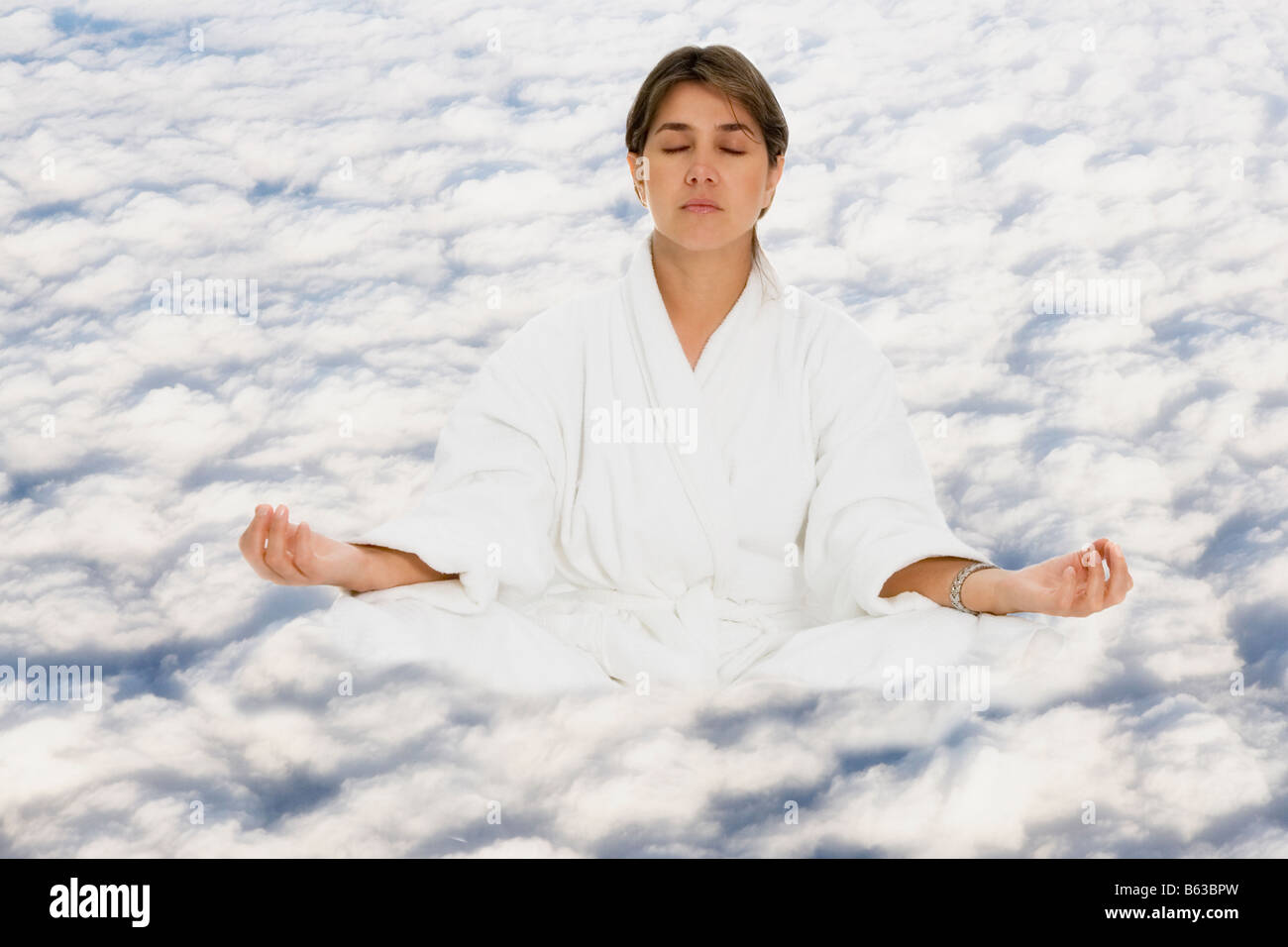 Mid adult woman practicing yoga on clouds Stock Photo