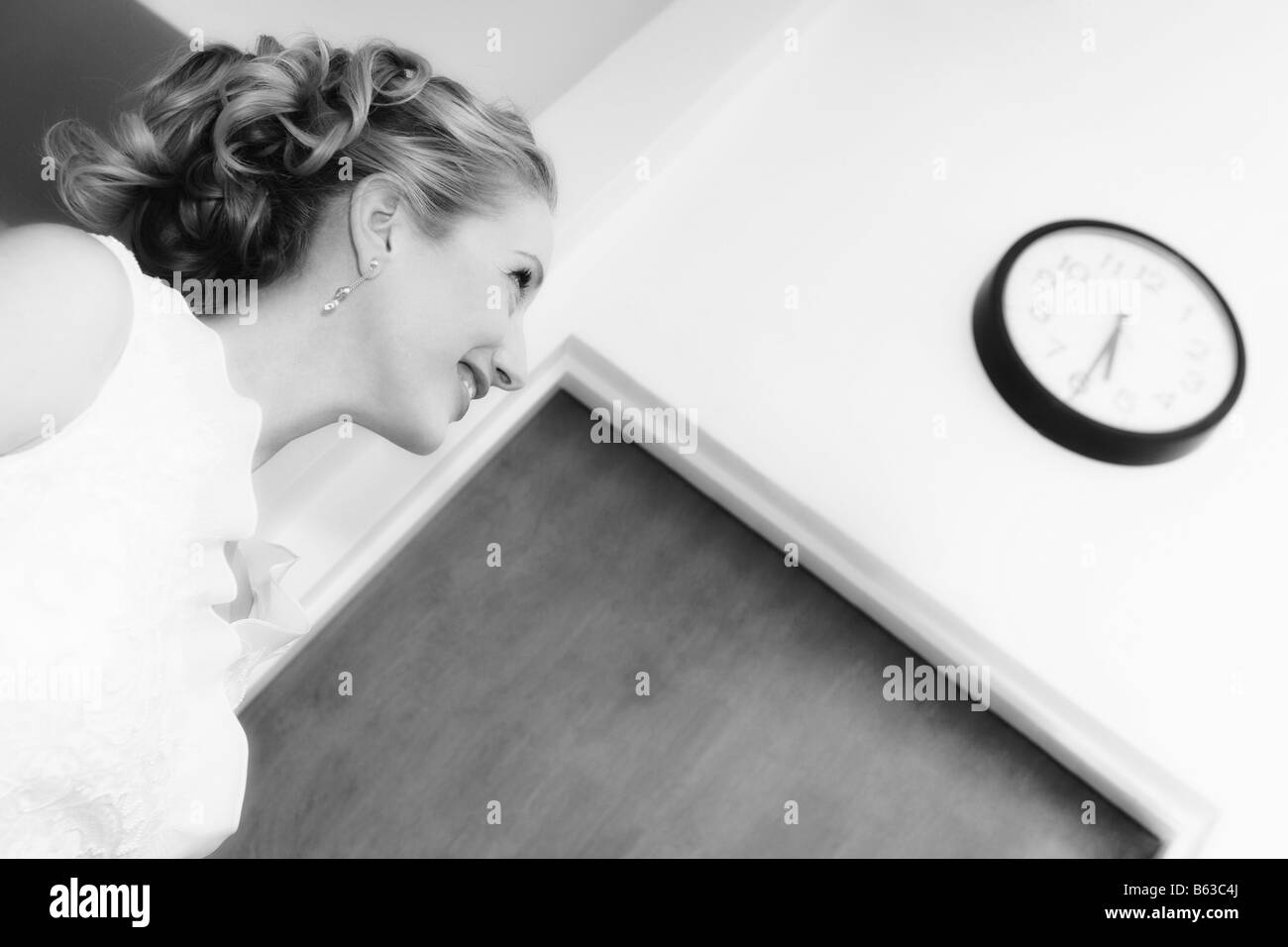 Side profile of a mid adult woman looking at a clock and smiling Stock Photo