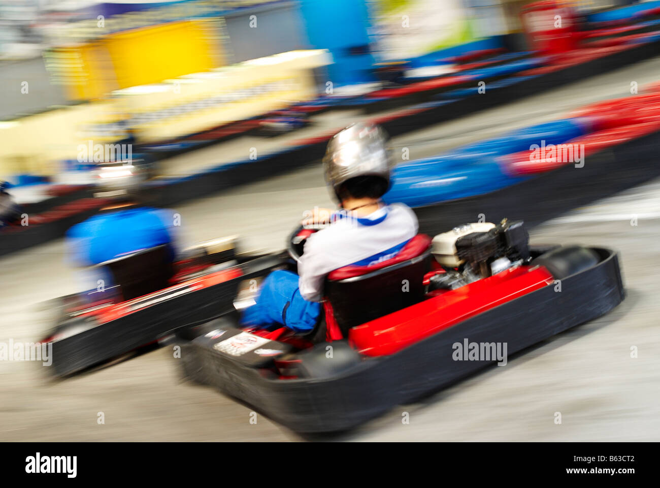 Rear view of two people go-carting on a motor racing track Stock Photo