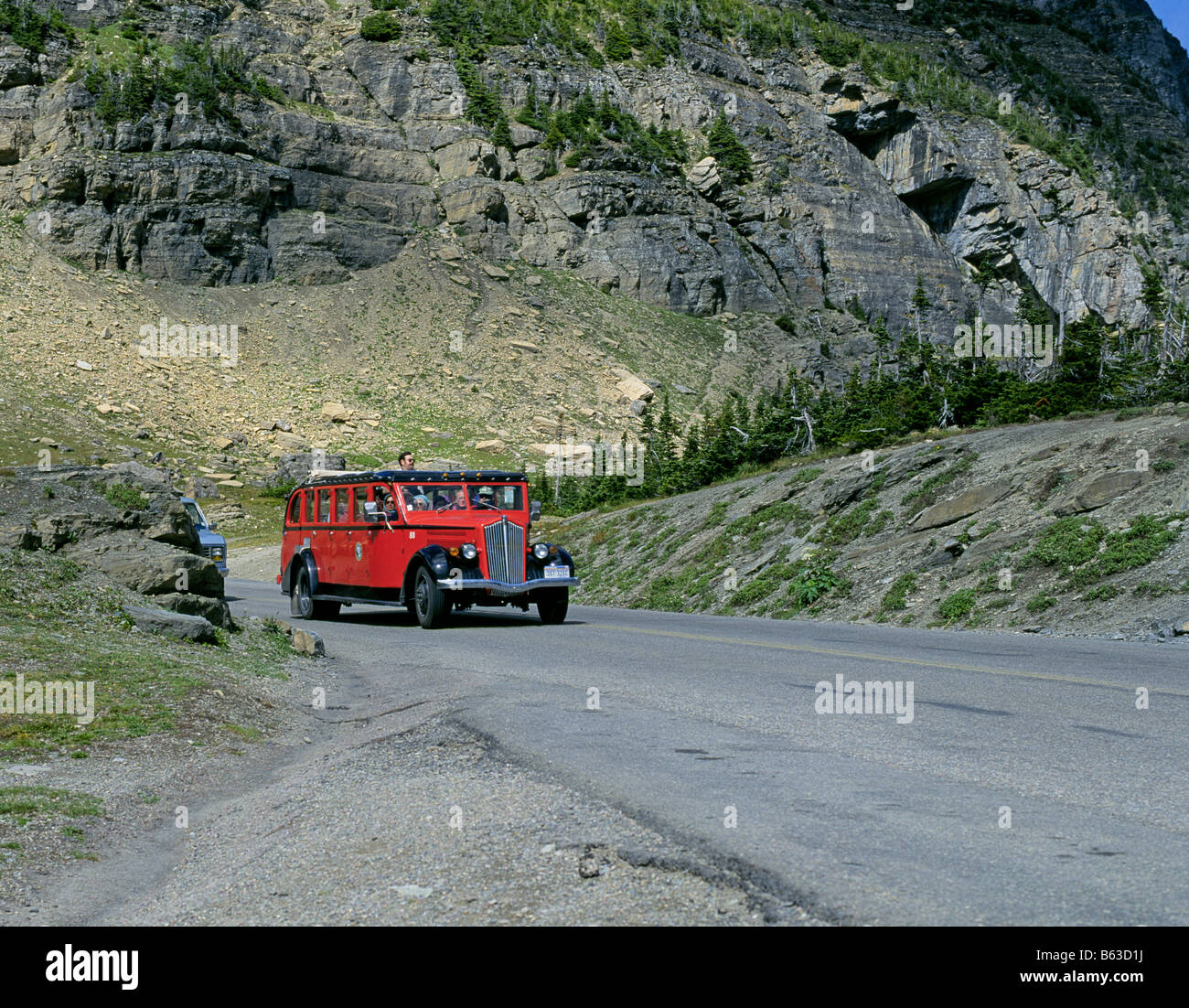 A white Motor Company Red Bus carries passengers on a tour of Going To The Sun Road, Glacier National Park Montana. Stock Photo