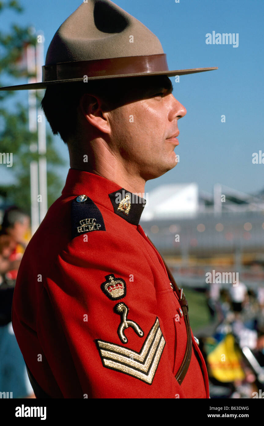 A Canadian Mountie (RCMP) Royal Canadian Mounted Police Officer wearing Traditional Red Serge Uniform and standing at Attention Stock Photo