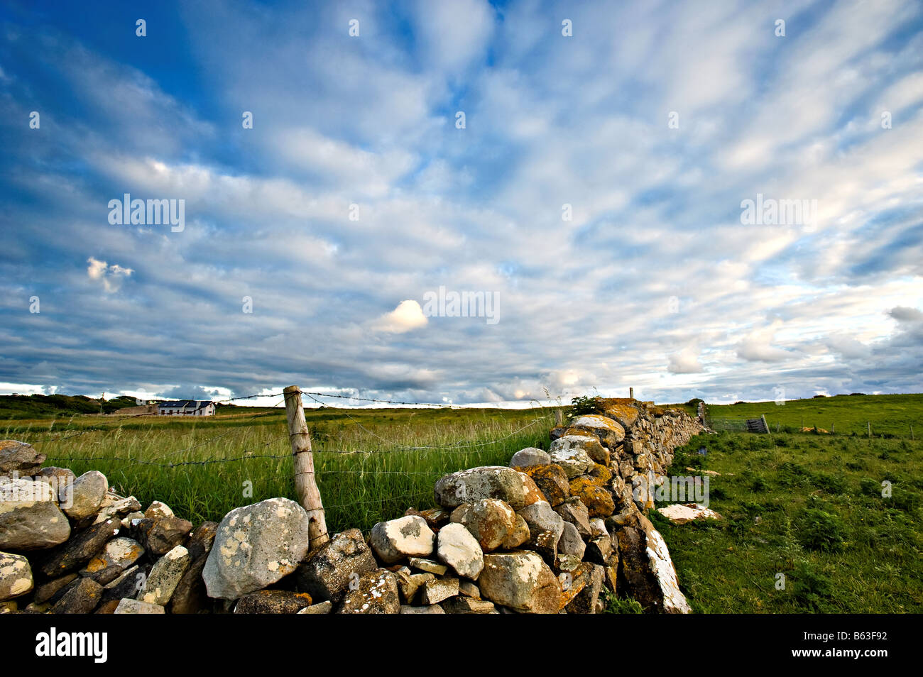 rural scene from Co.Sligo, Ireland shows stone wall topped with barbed wire fence Stock Photo