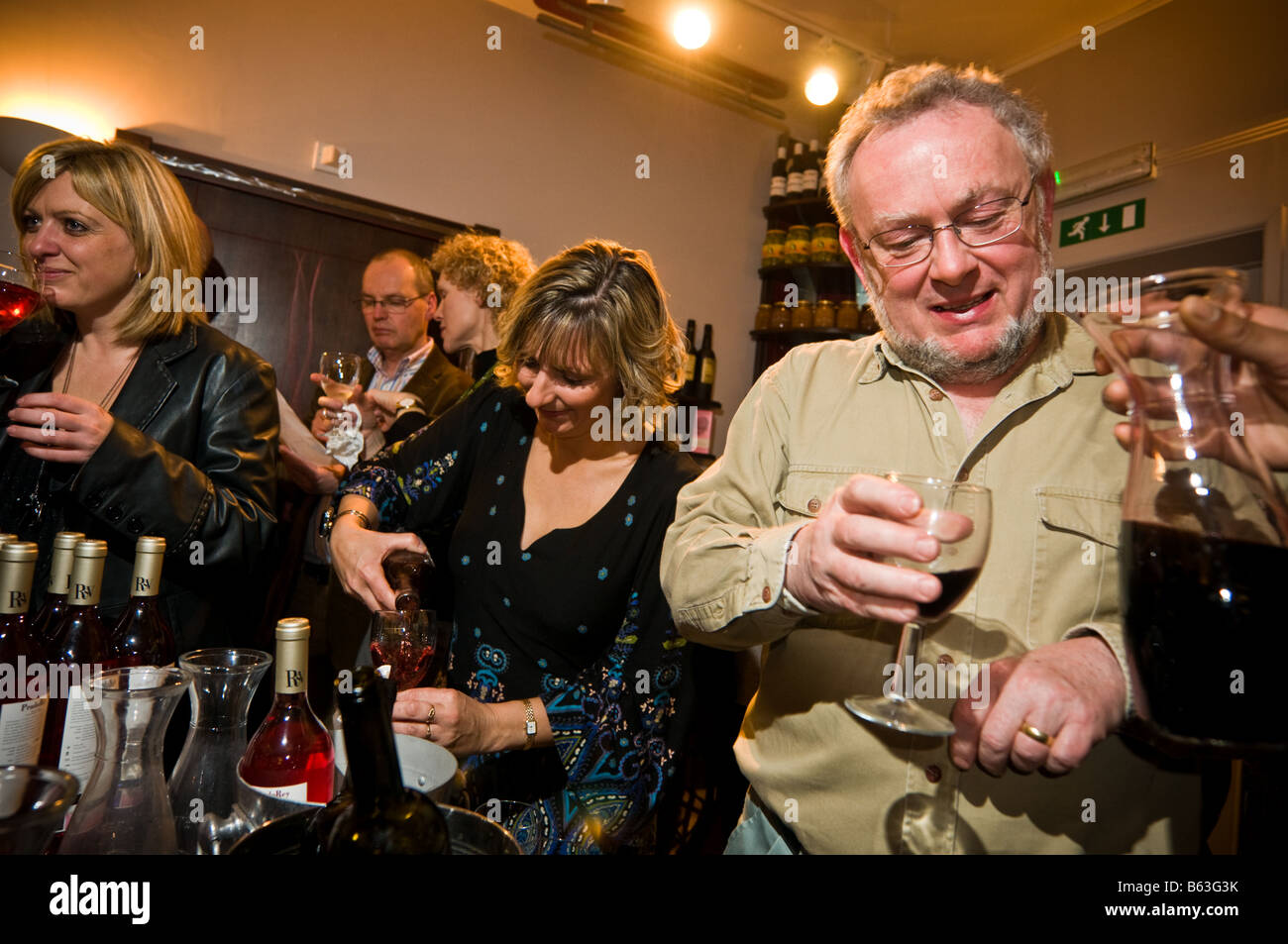 middle class people sampling drinks at a wine tasting evening in a restaurant drinking red wine, UK Stock Photo